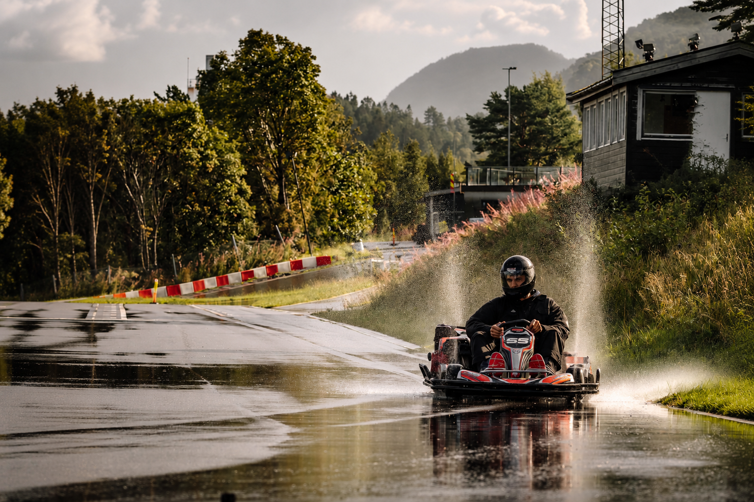 Gokart i full fart som spruter opp vann på Ålesund Kart Ring, med fjell i bakgrunnen